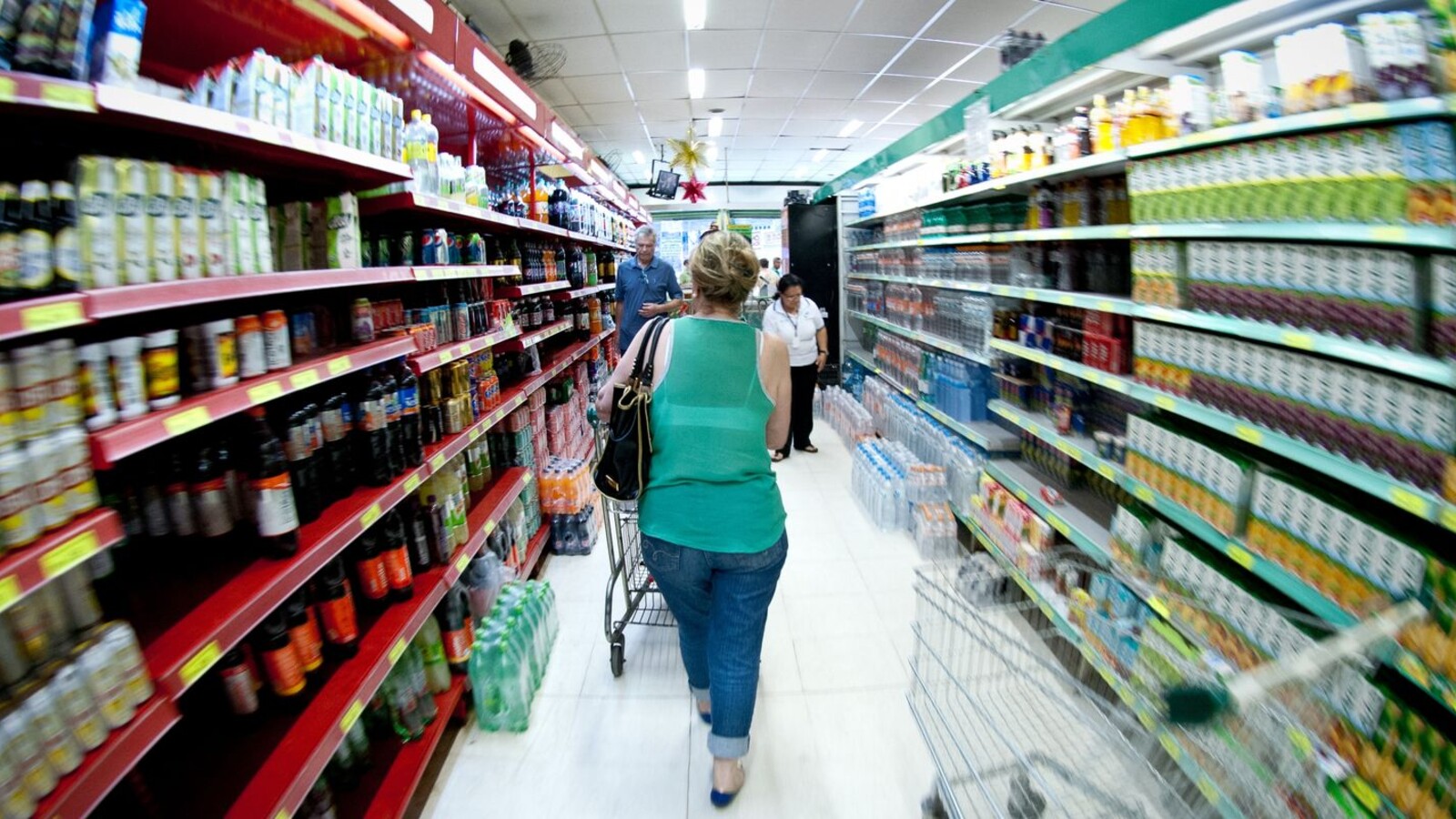 Consumidora observa produtos em uma prateleira de supermercado