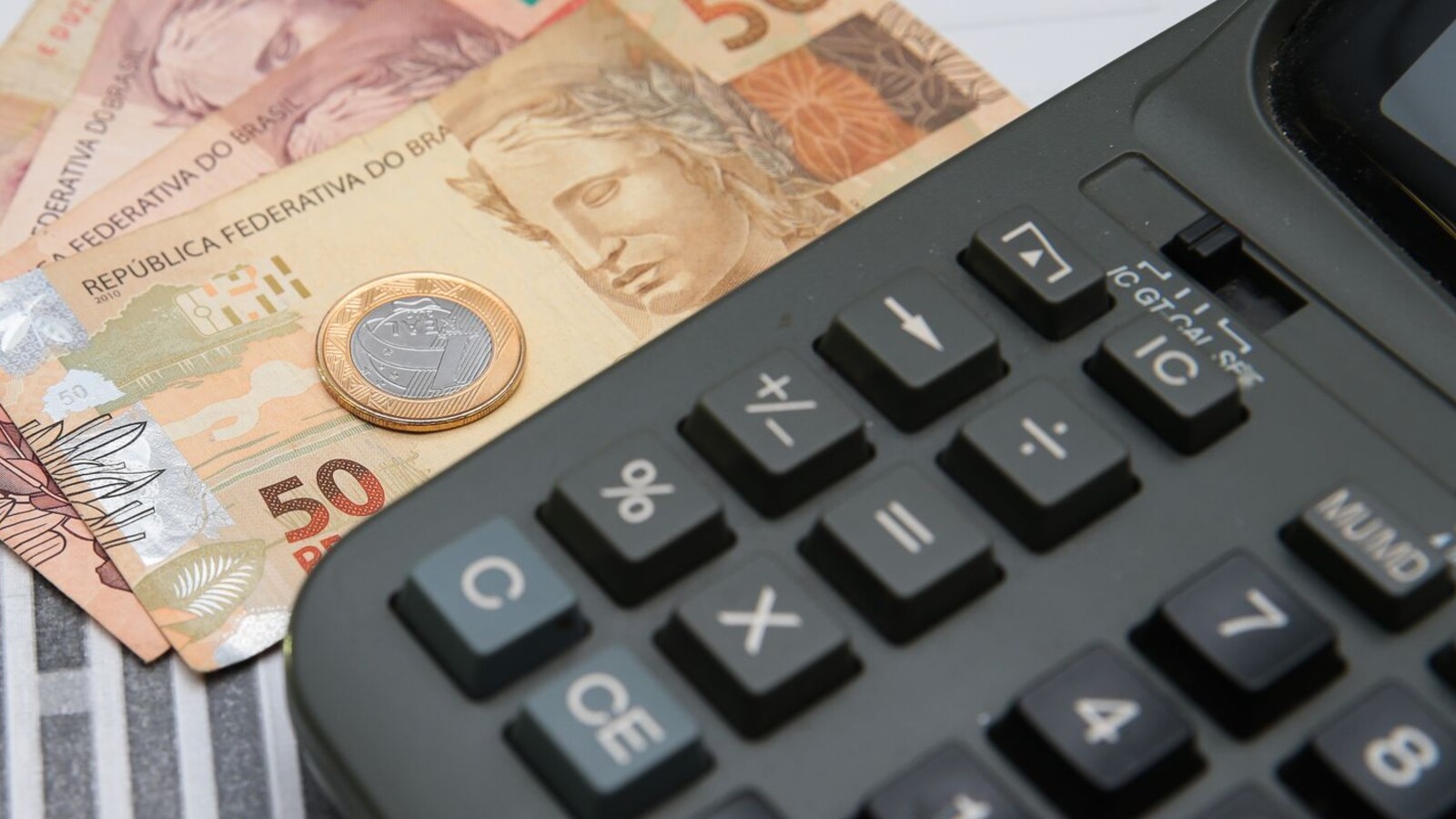 Calculadora, cédulas e moedas representam o planejamento tributário das pequenas empresas